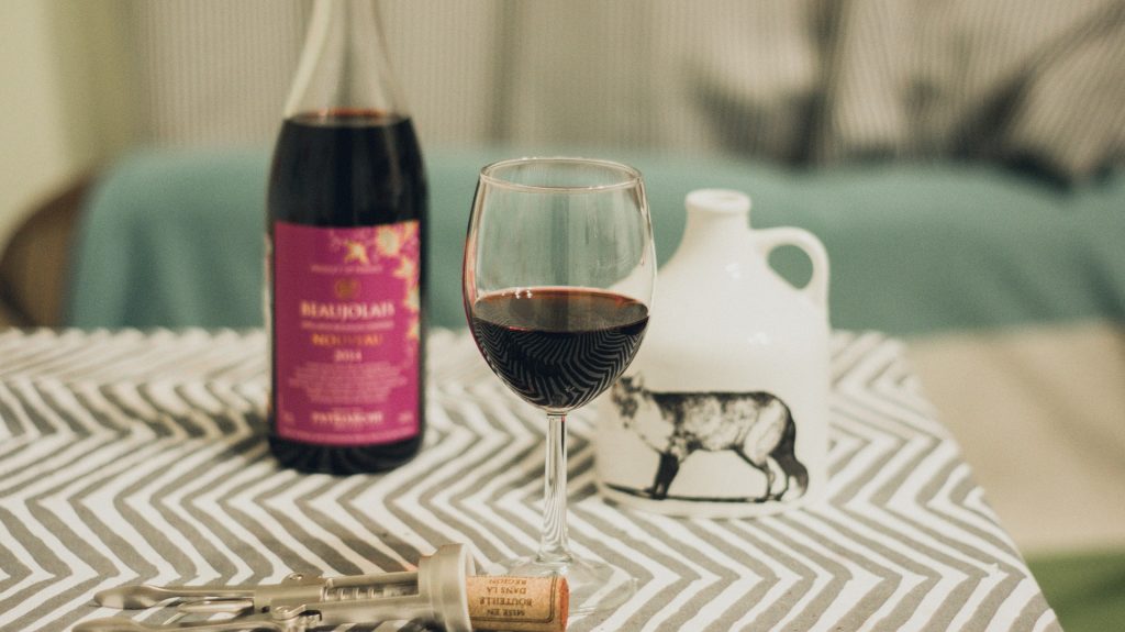 a glass of beaujolais red wine and bottle